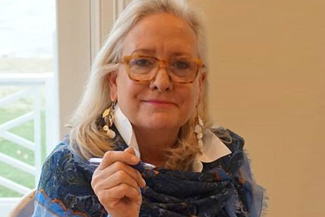 Woman with glasses and a blue patterned shawl wrapped around her shoulders 