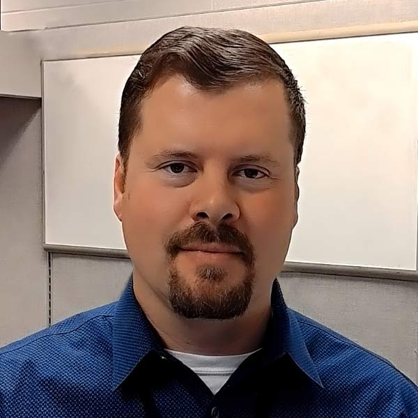 Man with a dark blue shirt smiling slightly