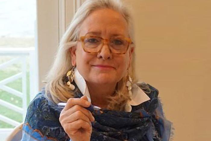 Woman with glasses and a blue patterned shawl wrapped around her shoulders