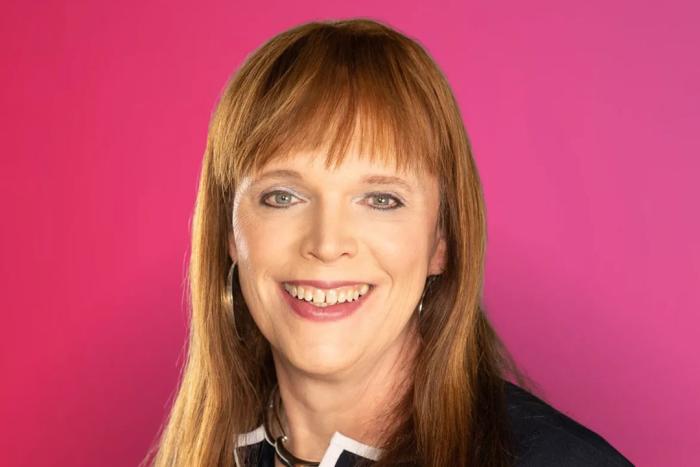 Woman with shoulder length hair and bangs smiling broadly