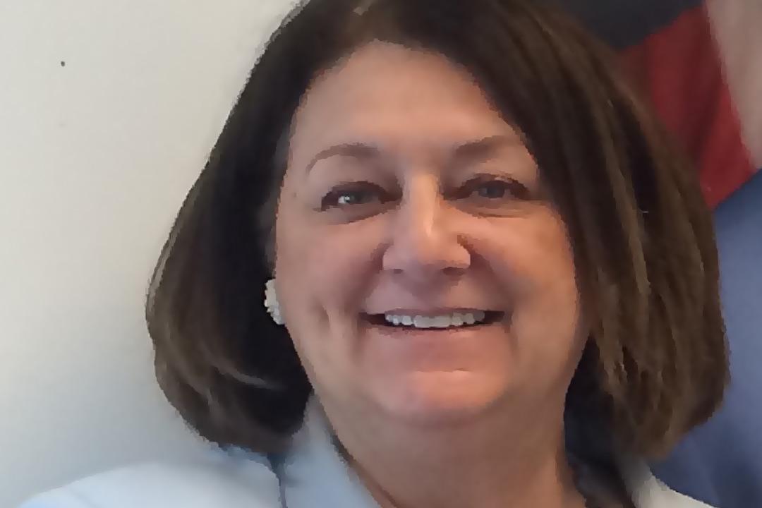 Woman with collar length brown hair looking ahead and smiling